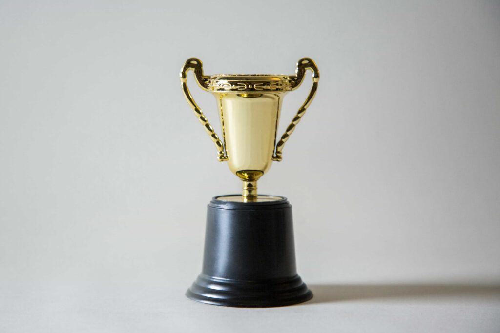 a golden coloured award trophy with two handles sitting on a black base