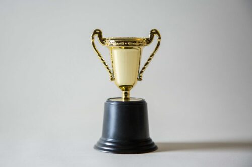 a golden coloured award trophy with two handles sitting on a black base