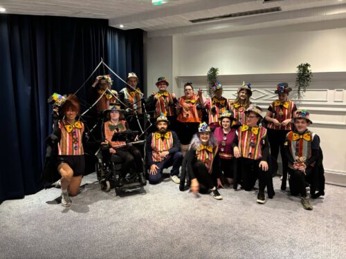 A group photo of men and women dressed in costume for a dance troupe parade